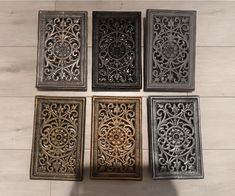 four metal square coasters sitting on top of a wooden floor