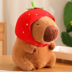 a stuffed animal with a strawberry hat on it's head sitting on a table