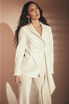 a woman in a white suit posing for the camera with her hands on her hips