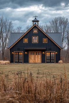 a large black barn with two windows and a steeple on the top of it