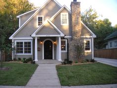 a gray house with white trim on the front door and two windows in the middle