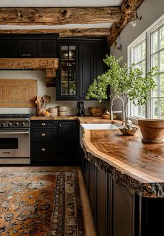 a kitchen with black cabinets and wooden counter tops, an area rug and potted plant