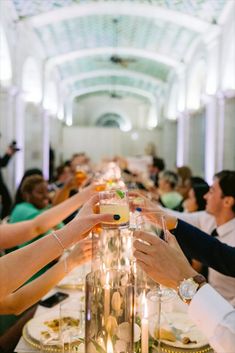 people are toasting with wine glasses on a long table