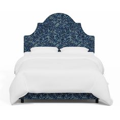 a bed with blue upholstered headboard and white linens on the sides