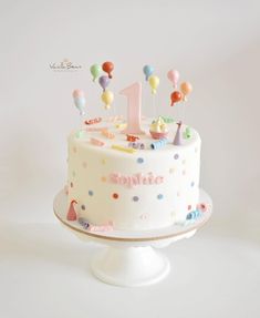 a birthday cake decorated with balloons and the number one is for someone's first birthday