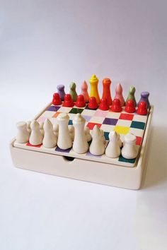 a wooden chess board with colorful pieces on the board and in front of white background