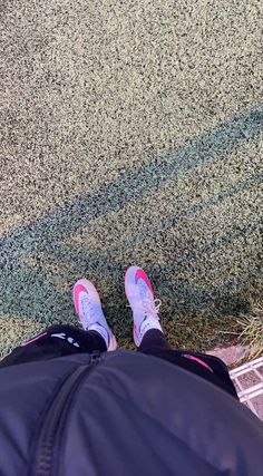 a person's feet with pink shoes standing on the ground next to a tennis court