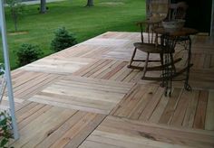 a wooden deck with rocking chair and table on it in front of a grassy area