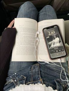 an open book sitting on top of a person's lap next to headphones