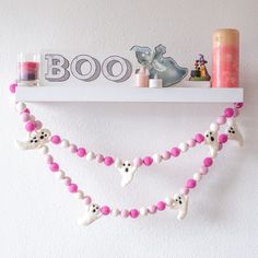 a white shelf with pink and white decorations on it's sides, along with candles