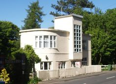 a large white building sitting on the side of a road next to a lush green forest