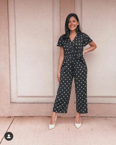 a woman standing in front of a door wearing a black and white polka dot jumpsuit