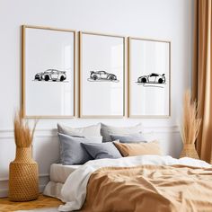 a bedroom with three framed cars on the wall above the bed and two vases