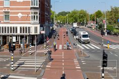 people are riding bikes down the street in front of buildings and cars on the road