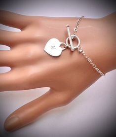 Sterling Silver heart tag Toggle Bracelet. All Metal Components onto 925 Sterling Silver. It could be engraved A-Z any initial , leave on "seller massage box" as you check out. IT is made of .. -Sterling Silver Toggle Clasp, - Sterling Silver Heart Tag pendent , -Sterling Silver cable chain, -Sterling Silver Toggle clasp,  -Come up with ribbon gift box , and -One set of Care instruction package . -it can be stamped custom initial. -All quantities are available for special occasion. MORE HEART NE Heart-shaped Jewelry Gift With Clasp, Heart-shaped Jewelry With Clasp For Gifts, Sterling Silver Toggle Clasp Bracelet Gift, Sterling Silver Bracelet With Toggle Clasp Gift, Sterling Silver Round Bracelet With Toggle Clasp For Gift, Adjustable Chain Bracelet With Toggle Clasp As Gift, Adjustable Sterling Silver Bracelet With Heart Charm As Gift, Sterling Silver Charm Bracelet With Toggle Clasp, Metal Bracelets With Clasp For Gifts