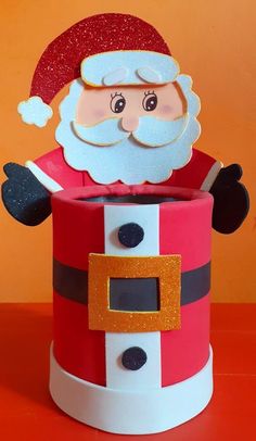 a santa clause is sitting in a red and white box with gold trimmings