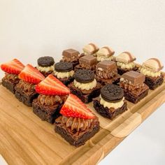 a wooden tray topped with brownies and strawberries