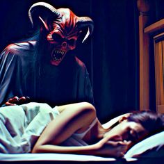 a woman laying in bed next to a demon