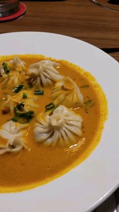 a white plate topped with soup and dumplings