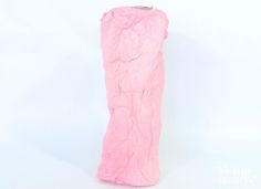 a pink object is sitting on a white surface and it appears to be made out of paper