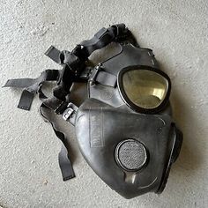 a gas mask that has been left on the floor with some pieces missing from it