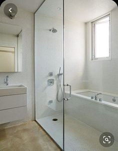 a bathroom with a walk in shower next to a white sink and bathtub under a window