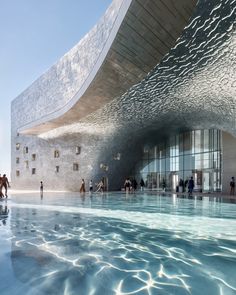 people are walking around in the water near a large building with a curved roof and glass windows