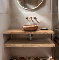 a bathroom sink with a wooden bowl on the counter and mirror in the corner above it