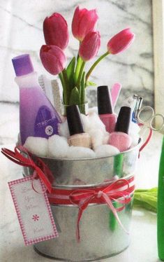 pink tulips are in a silver bucket with soap and lotion on the counter