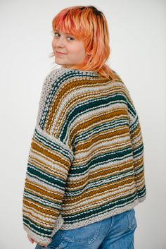 a woman with red hair wearing a multicolored sweater