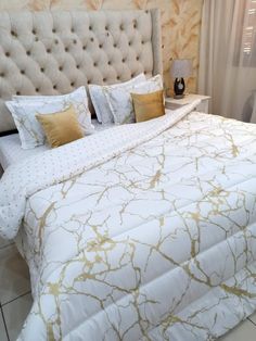 a bed with white and gold comforter in a bedroom