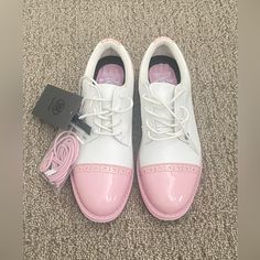 a pair of white and pink tennis shoes on the ground next to a black box