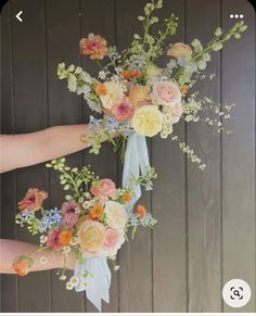 two bouquets of flowers are being held up by someone's hand on a wooden background