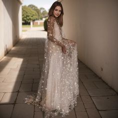 a woman in a long white dress standing on a brick walkway with her hands on her hips