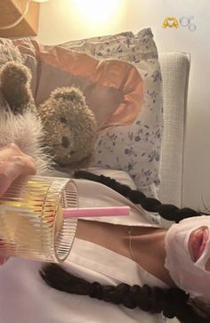 a woman laying on top of a bed with a teddy bear next to her face