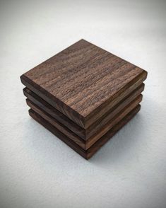 four square wooden coasters stacked on top of each other, one is brown and the other is black