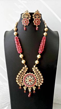 Gather compliments wearing this high quality, beautiful and unique Indian kundan ruby necklace set with ruby colored stone necklace, large pearls and tiny seed pearls with gold beads and ruby red beads scattered here and there. The ruby color is very pretty red with pinkish tones. It is sure to dazzle and elevate any outfit to the spectacular. Necklace measures drop of 10 inches. Pendant measures 4 x 4 inches. S hook closure. Gorgeous matching earrings in a very attractive shape. Length 2 1/2 in Kundan Pearl Necklace For Celebration, Red Kundan Bridal Necklace For Reception, Red Kundan Temple Necklace With Stone Work, Festive Ruby Chandbali Necklaces, Ruby Kundan Necklace With Intricate Design For Diwali, Ruby Kundan Necklace With Intricate Temple Jewelry Design, Pink Kundan Temple Necklace For Wedding, Festive Ruby Chandbali Necklace, Red Jeweled Kundan Necklace For Wedding