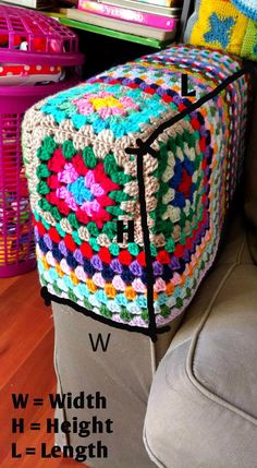 a crocheted granny blanket sitting on top of a couch next to a pink basket