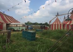 an old circus tent is set up in the middle of a grassy area with several tents