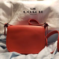 Mini Coach Purse In Coral. Excellent Condition, Never Used. Can Be Worn As A Shoulder Or Crossbody Bag With Adjustable Strap, Flap Opening With Pocket In The Front And A Zip Compartment And A Pocket In The Back. Comes With Dust Bag To Protect It When Not In Use. Dimensions: 52" Strap When Used As Crossbody Purse And 26" When Used As Should Bag (See Picture) Width: Approximately 7 1/2 Inches Height: 6 Inches Thickness Top 2 Inches Bottom 3 Inches It Also Has A Loop For Keys On The Side Designer Saddle Bag For Shopping, Designer Saddle Bag, Chic Red Saddle Bag With Detachable Strap, Red Saddle Bag For Formal Occasions, Coach Top Handle Shoulder Bag As Gift, Coach Leather Bags As A Gift, Coach Designer Crossbody Shoulder Bag, Designer Coach Crossbody Shoulder Bag, Coach Bags Perfect As Gifts