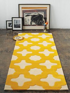 a yellow and white rug on the floor in front of a black and white photo