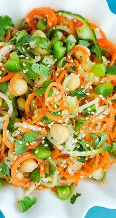 a salad with carrots, celery, and peanuts on a white plate