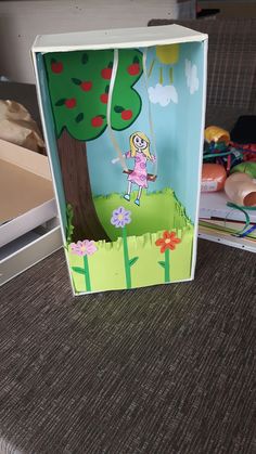 an open box with a paper cutout of a girl in the park on it