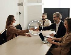 people sitting at a table shaking hands with each other in front of a laptop computer