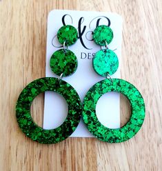 two green earrings on top of a wooden table