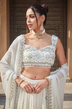 Ivory lehenga with chikankari embroidered stripe and scallop motifs embellished by sequins. Comes with mirrorwork embroidered blouse and cut-out border dupatta. - Aza Fashions Designer White Lehenga With Chikankari Embroidery, Sleeveless Lehenga With Chikankari Embroidery For Festive Occasions, White Choli For Eid Reception, White Sharara For Wedding And Navratri, White Anarkali Lehenga With Chikankari Embroidery, Designer Chikankari Embroidered White Lehenga, Sleeveless Lehenga With Chikankari Embroidery For Diwali, White Lehenga With Chikankari Embroidery For Festive Occasions, White Embroidered Choli For Reception