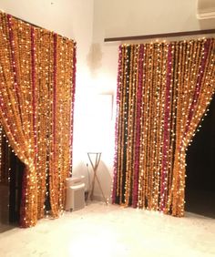 the room is decorated with gold and red beaded curtains, black doors, and a toilet