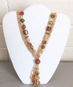 This is a vintage multi-strand glass bead tassel necklace. It has large bead strands and seed bead strands. The glass beads are in earth tone multi-colors; orange to rust, green, amber, some gold metal beads between the glass beads and some white beads.  It is 28" from end to end, the tassel portion adds another 4". It is in very good condition, without any noticeable wear.       See photos to evaluate condition. Orange Multi-strand Beaded Necklaces, Orange Multi-strand Beaded Necklace, Bohemian Amber Multi-strand Beaded Necklace, Multi-strand Czech Glass Beaded Necklace, Orange Multi-strand Bohemian Beads, Brown Multi-strand Beaded Chain Necklace, Brown Multi-strand Necklace With Colorful Beads, Brown Multi-strand Beaded Necklace, Gold Beaded Multi-strand Lariat Necklace