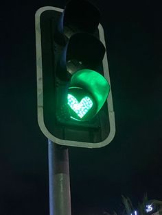 a traffic light with a green heart on it's side at night time,