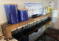 two blue mugs sitting on top of a wooden shelf next to a glass stove